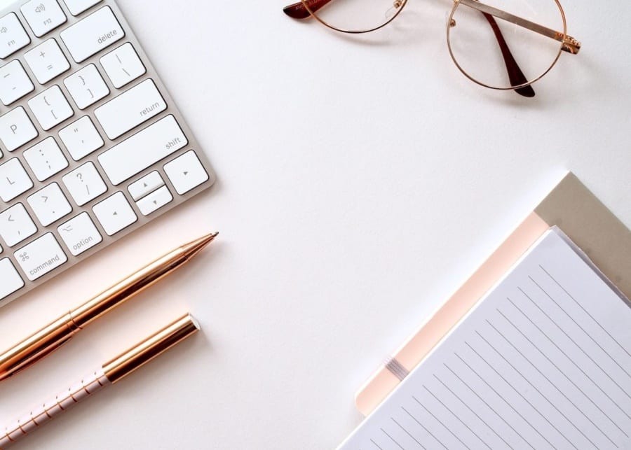 keyboard notebook pen reading glasses on a table